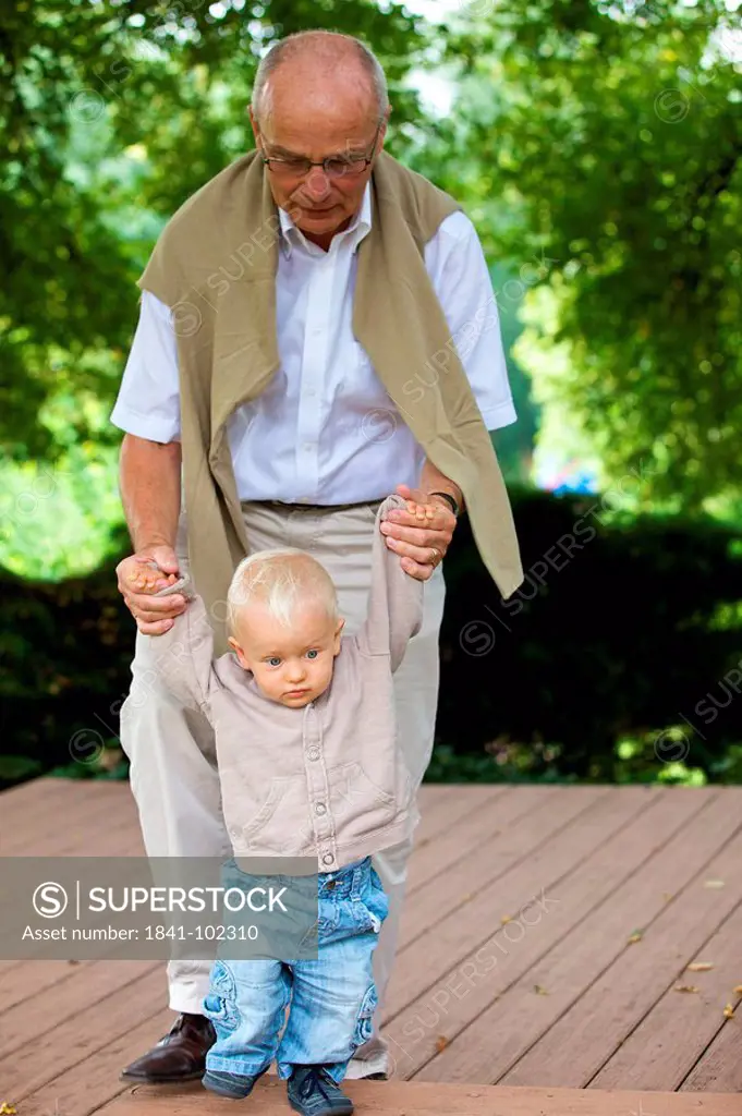 Grandfather helping toddler to walk