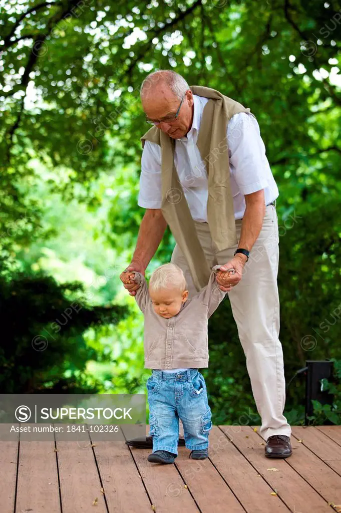 Grandfather helping toddler to walk