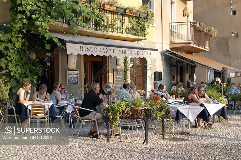 Tourists sitting at sidewalk cafe in town, Malcesine, Lake Garda, Italy