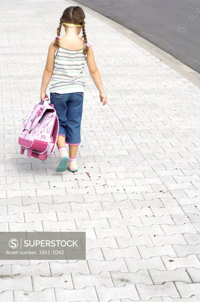 Rear view of girl carrying schoolbag at roadside