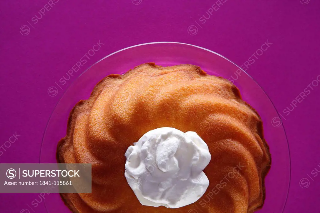 Ring_shaped cake with cream blob on glass plate
