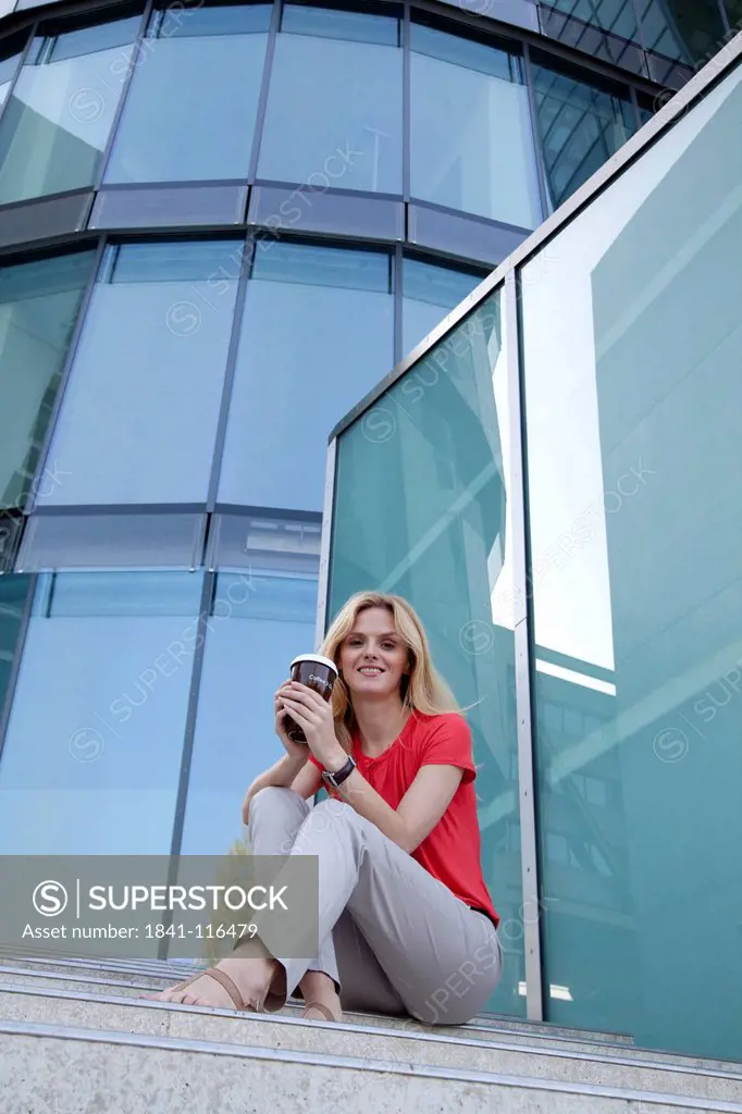Blond woman with coffee to go on stairs