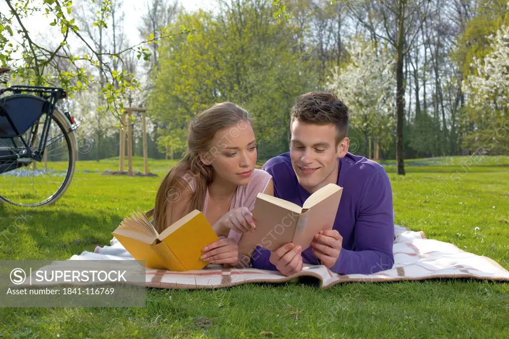 Young couple reading on a meadow