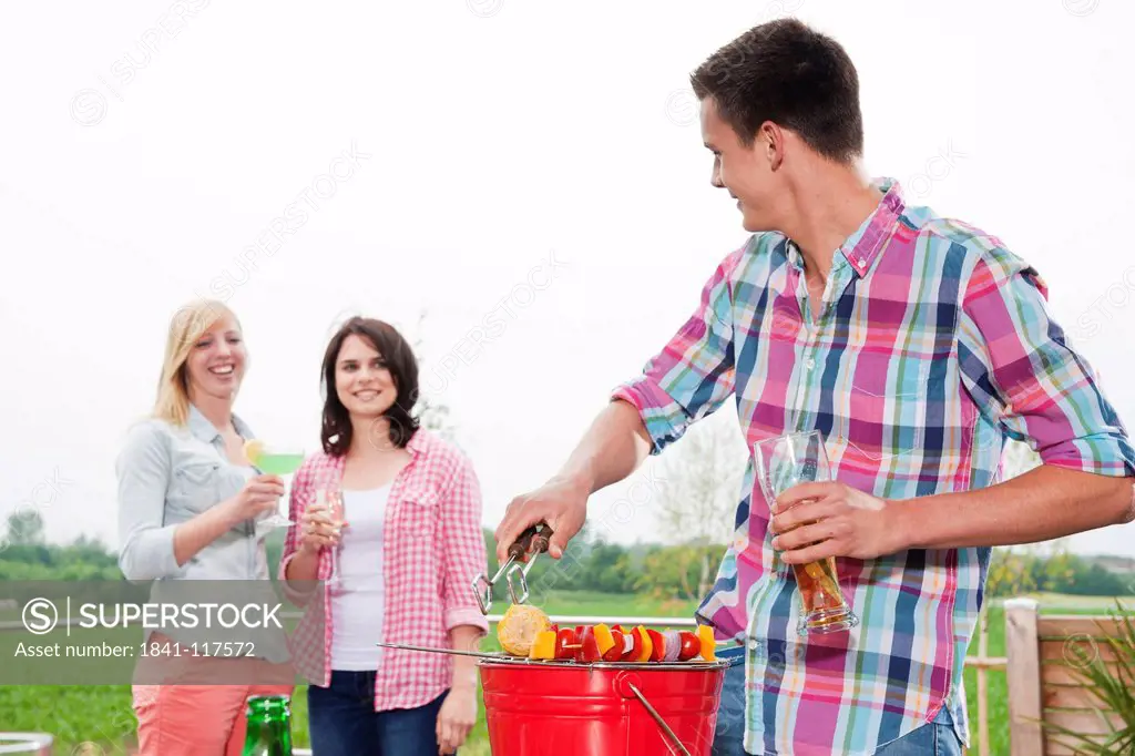 Friends barbecueing on a bucket