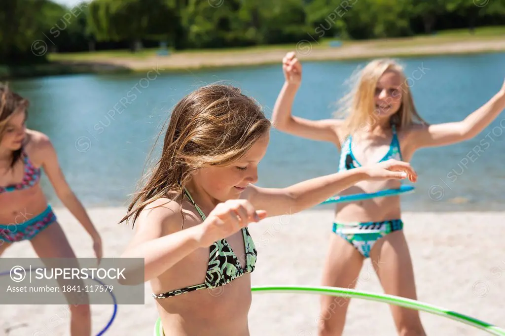 Three girls in bikinis with hula hoops at bathing lake