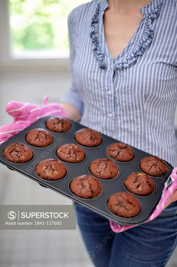 Woman holding baking plate with muffins