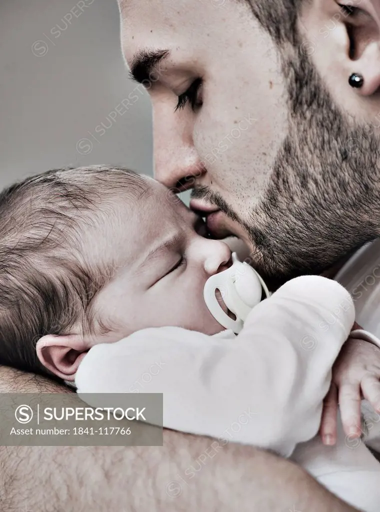Father kissing two weeks old baby
