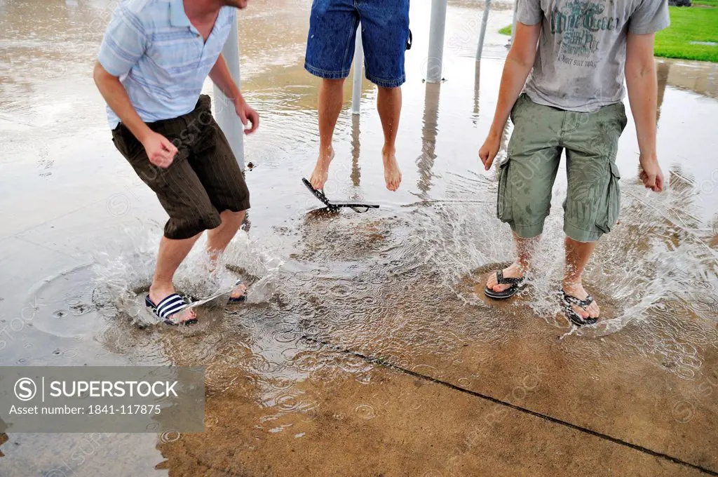 Three young men jumping in puddles