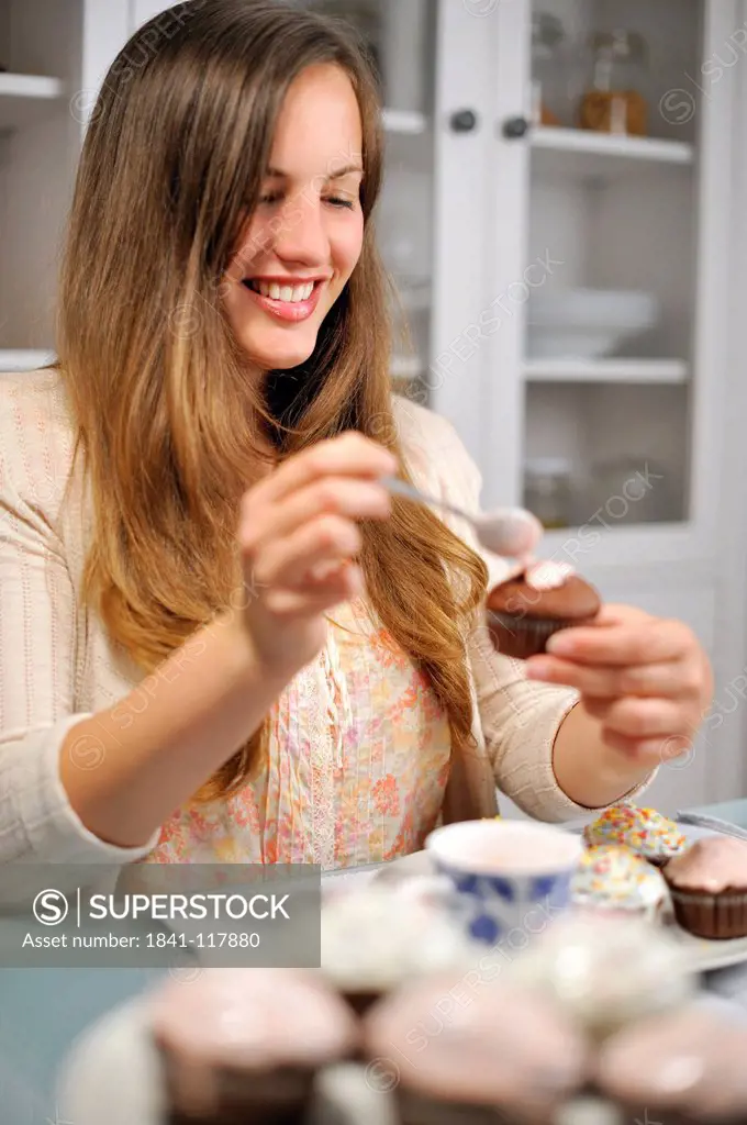 Young woman garnishing muffin