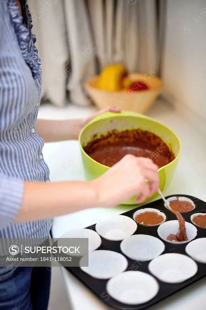 Woman baking muffins in kitchen