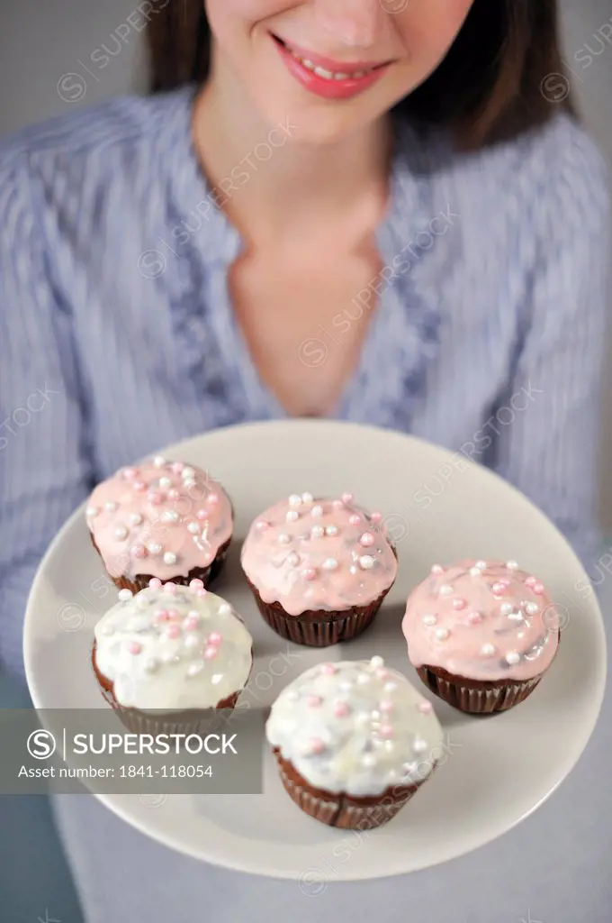 Woman holding plate with five muffins