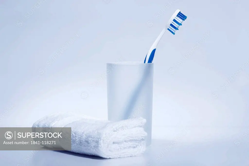 Toothbrush in toothbrush tumbler beside white towel
