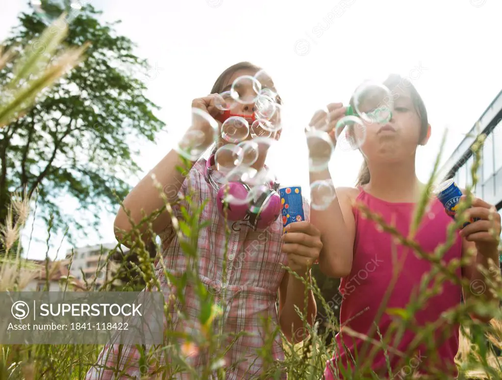 Two girls blowing soap bubbles