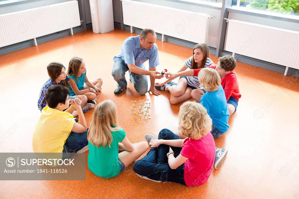 Schoolchildren and teacher sitting together in circle