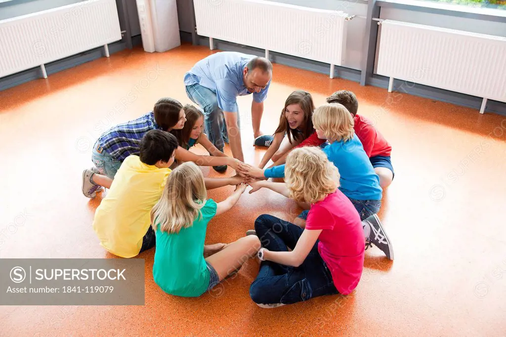 Schoolchildren and teacher sitting together in circle