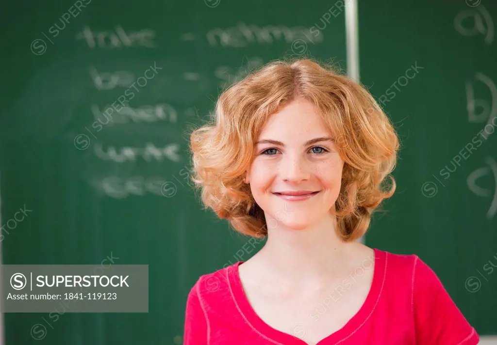Smiling teenage girl in classroom, portrait