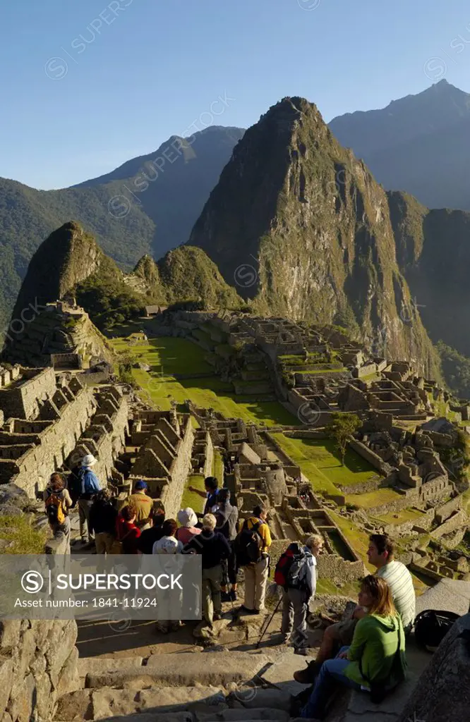 Tourists looking at old ruins on mountain, Inca Ruins, Machu Picchu, Cusco Region, Peru