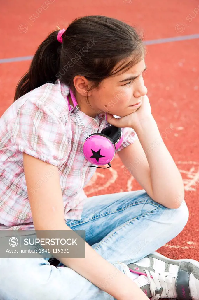 Serious girl sitting on schoolyard