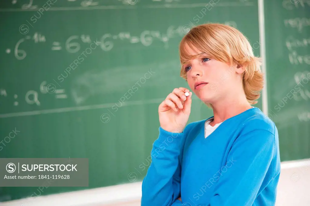 Schoolboy at blackboard thinking about formula