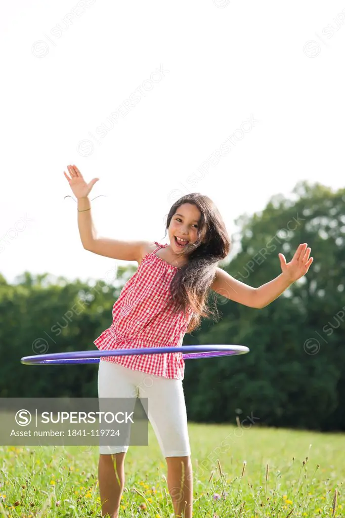 Girl with hula hoop on meadow