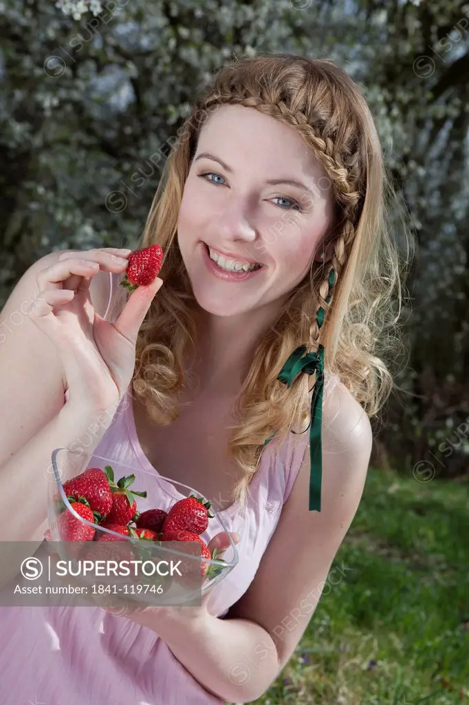Blond woman holding strawberries in her hand