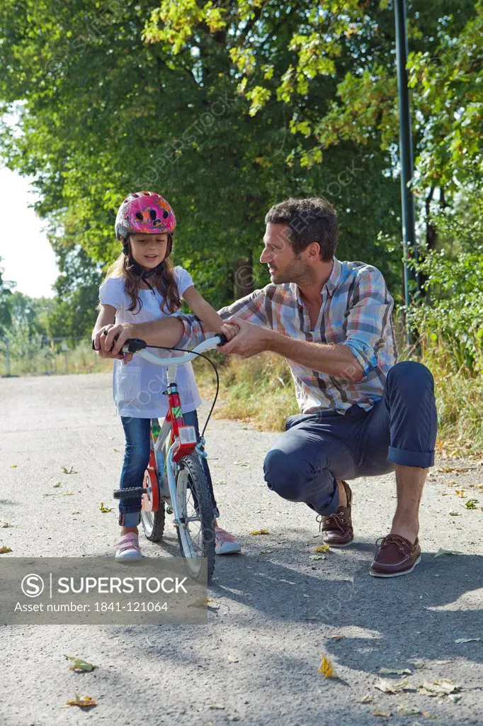 Father and daughter with helmet on bike outdoors