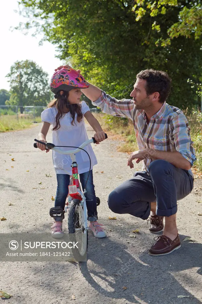 Father and daughter with helmet on bike outdoors