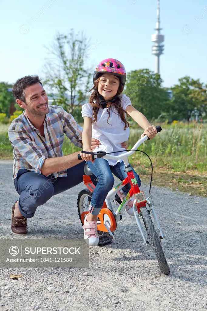 Father holding daughter on bike outdoors
