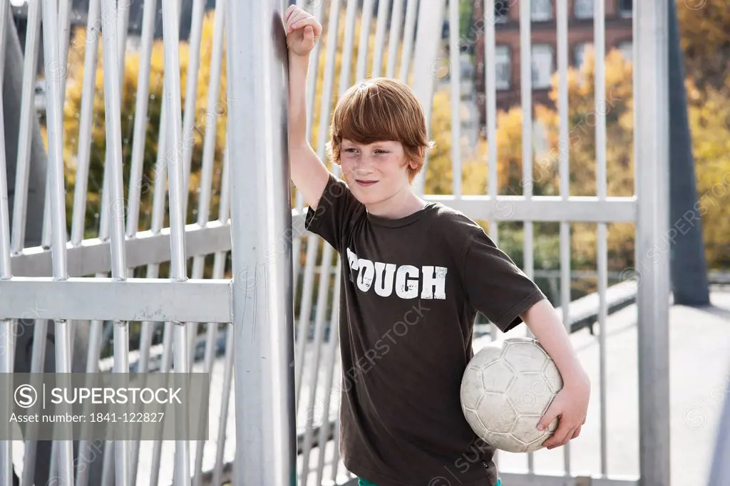 Boy standing with football on sports ground