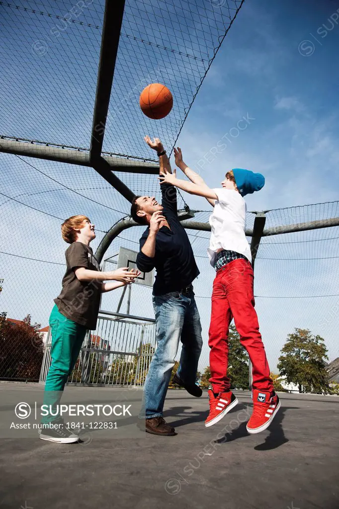 Father and two sons playing basketball
