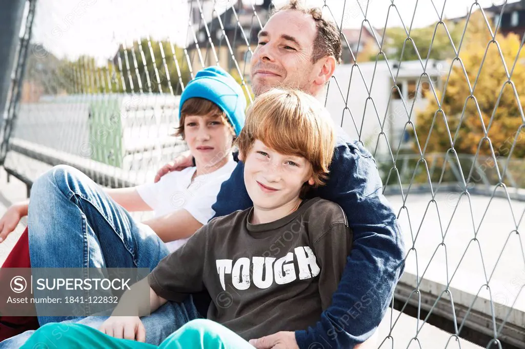 Father and two sons on sports ground