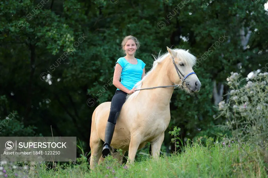 Smiling girl riding on horse