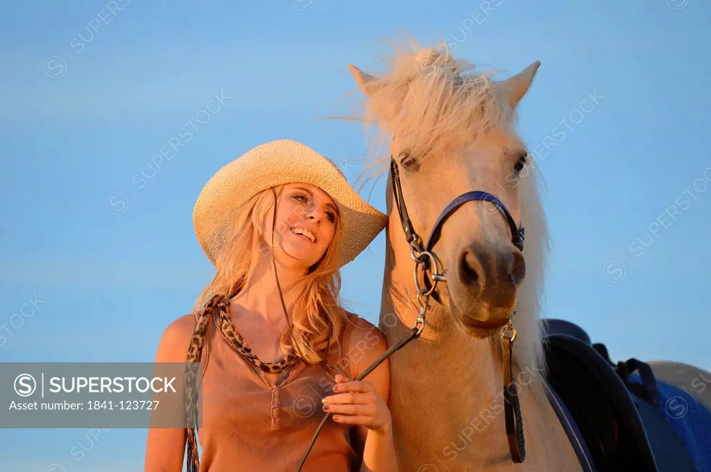 Smiling woman with horse under blue sky