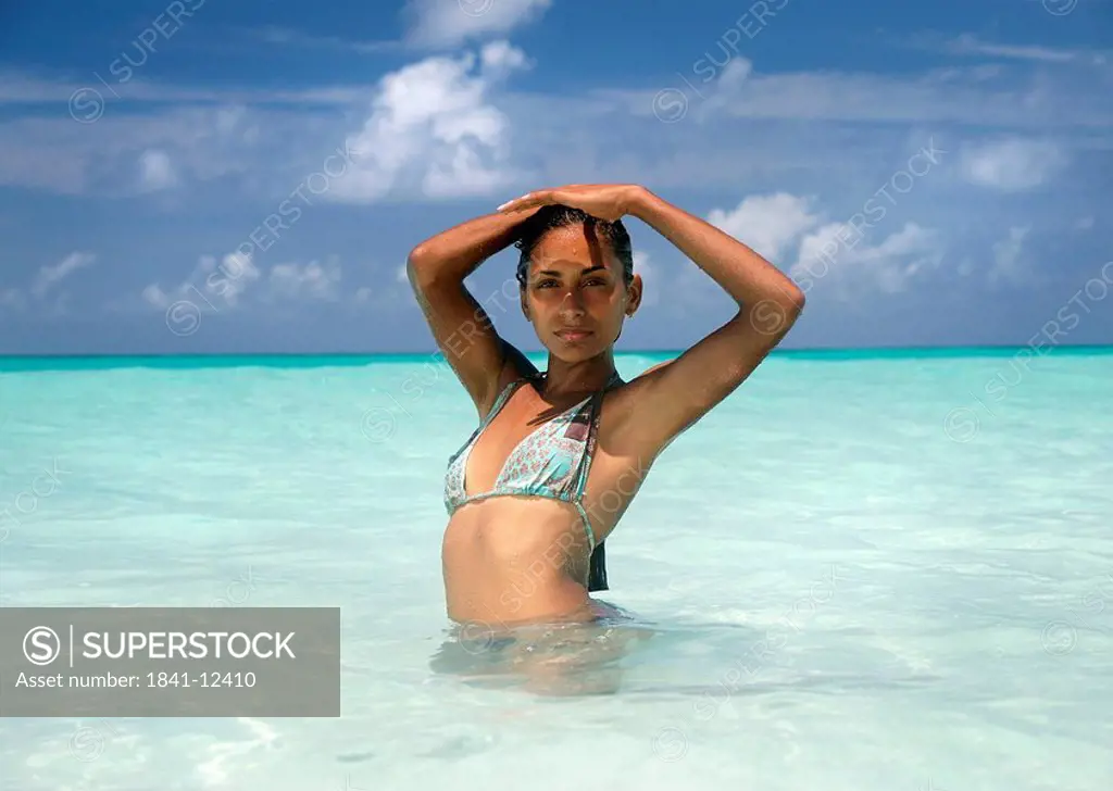 Woman standing in the water and shading eyes with her hands
