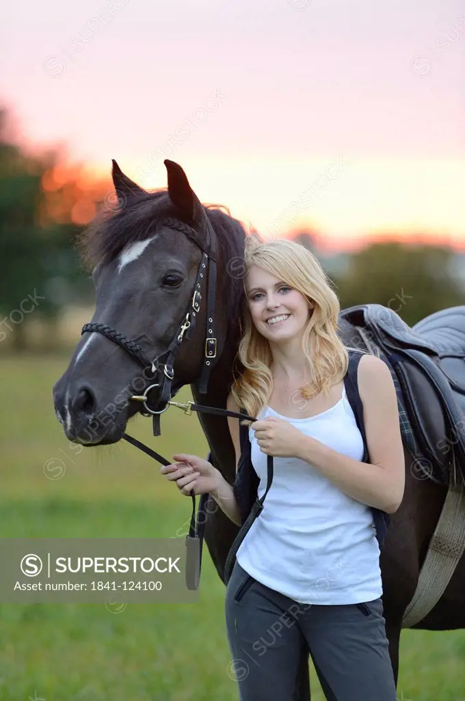 Smiling woman with horse on meadow