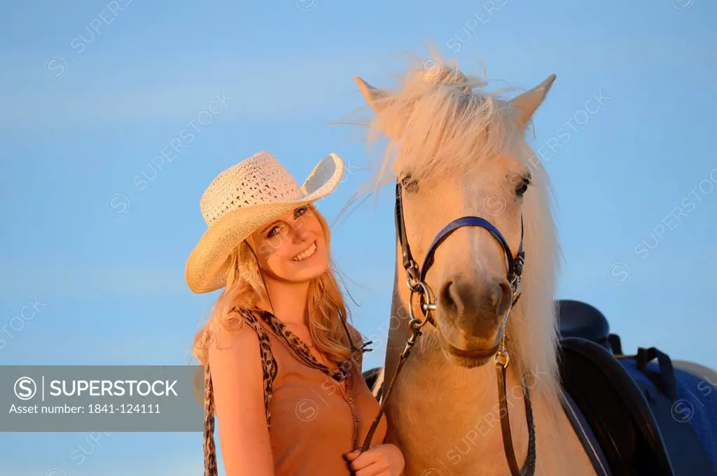 Smiling woman with horse under blue sky, portrait