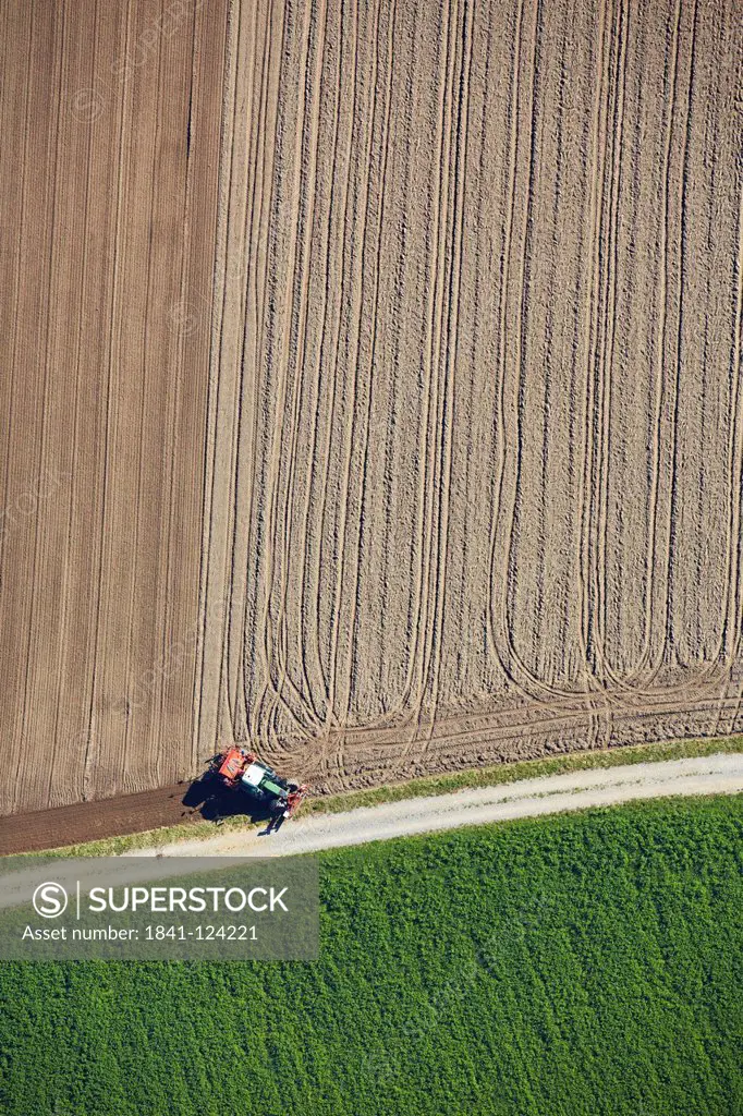 Tractor between field and meadow, aerial photo