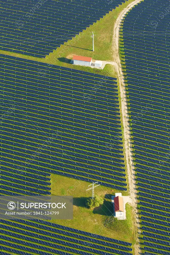 Solar panels, houses and electricity pylons on a field, aerial photo