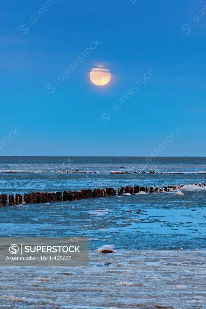 Full moon above the Wadden Sea covered with ice floes in Keitum, Sylt, Germany