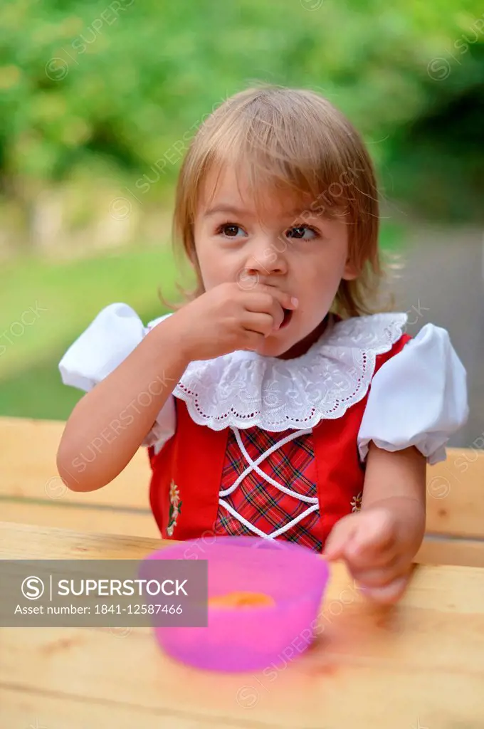 Young girl eating fruit.