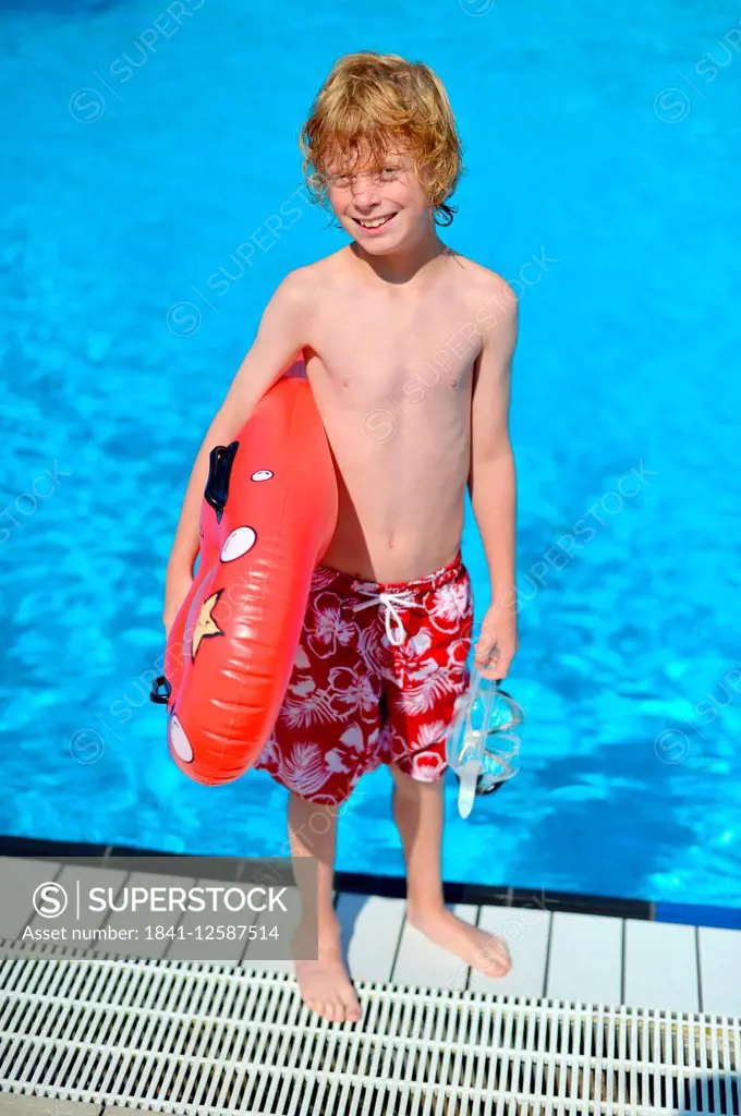 A boy with a swimming board in an open air bath.