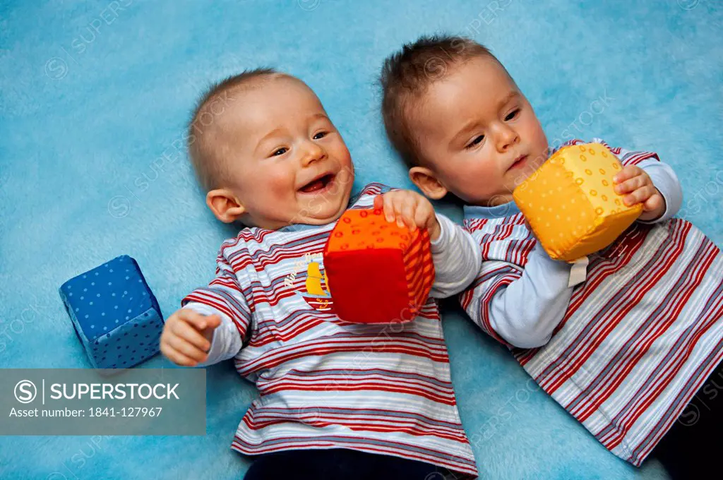 6 month old twins are playing on a blue blanket