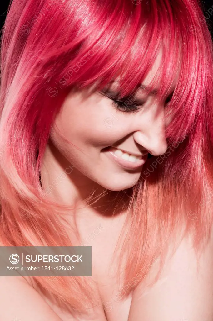 Smiling red-haired young woman looking down