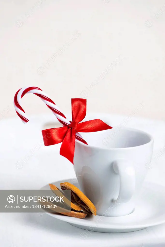 Cup decorated with candy cane, red ribbon and dried slices of orange