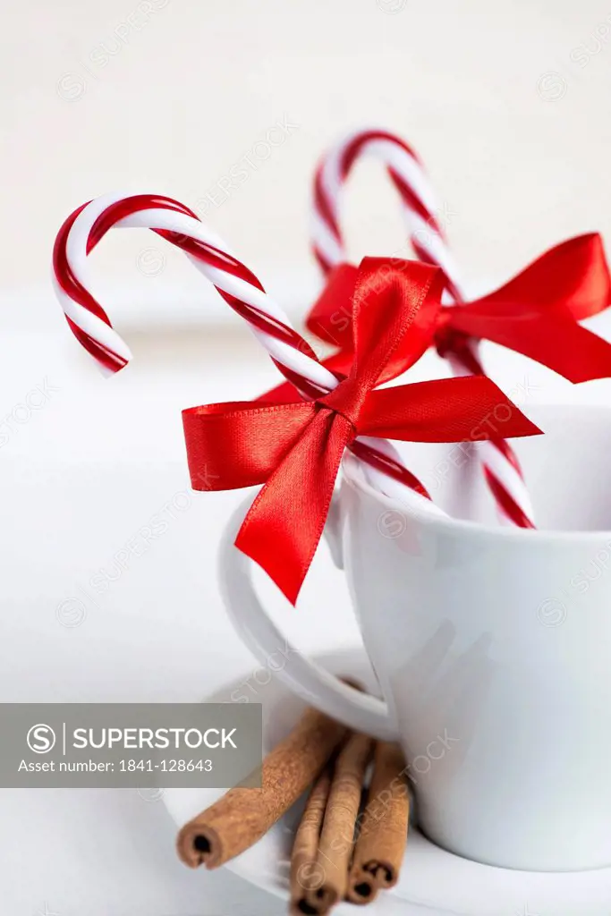 Cup decorated with candy canes, red ribbon and cinnamon sticks