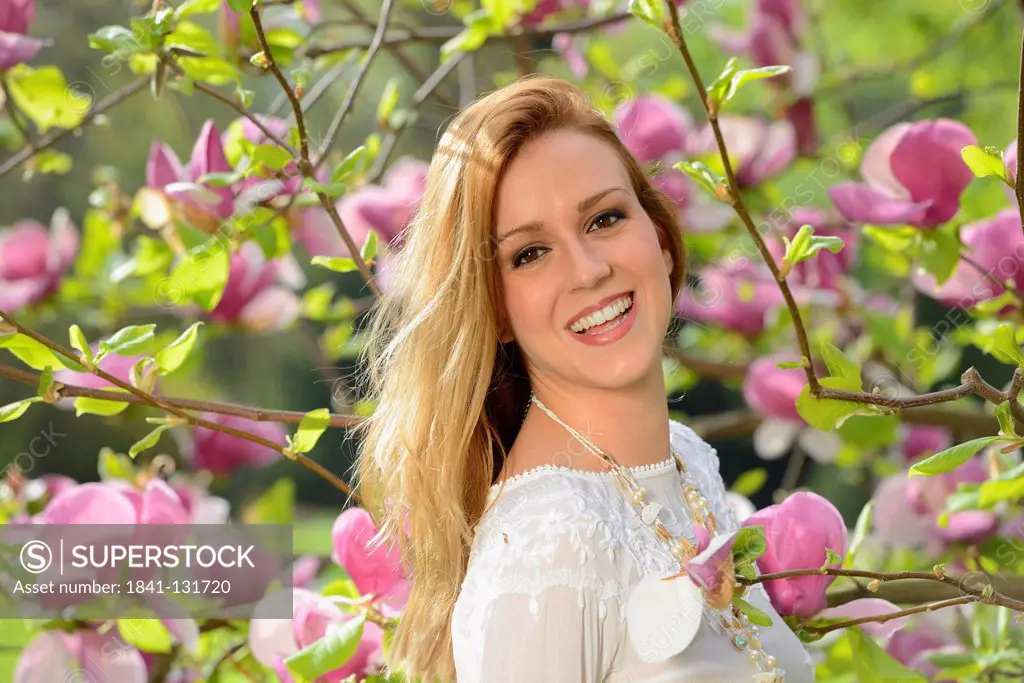Headline: Young woman at a flowering magnolia, portrait