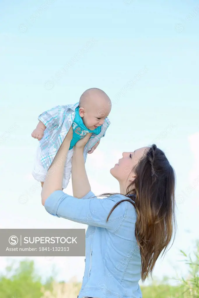Headline: Happy mother holding baby outdoors