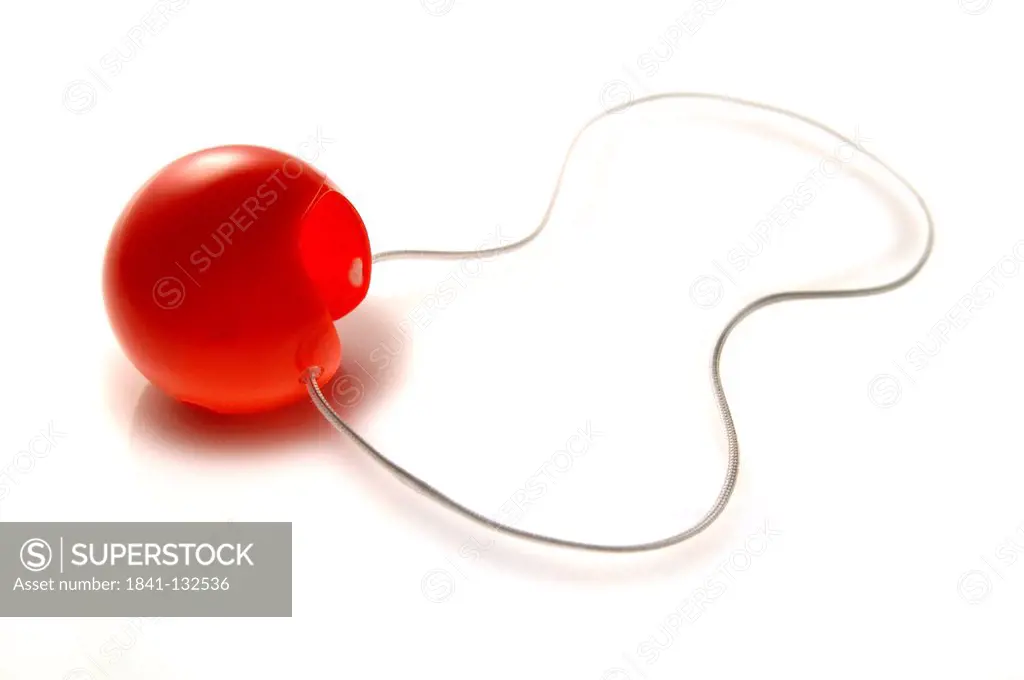 Red clown nose with elastic band on white background.