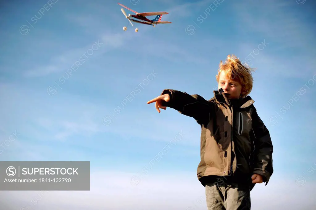 A boy is playing with a model airplane.