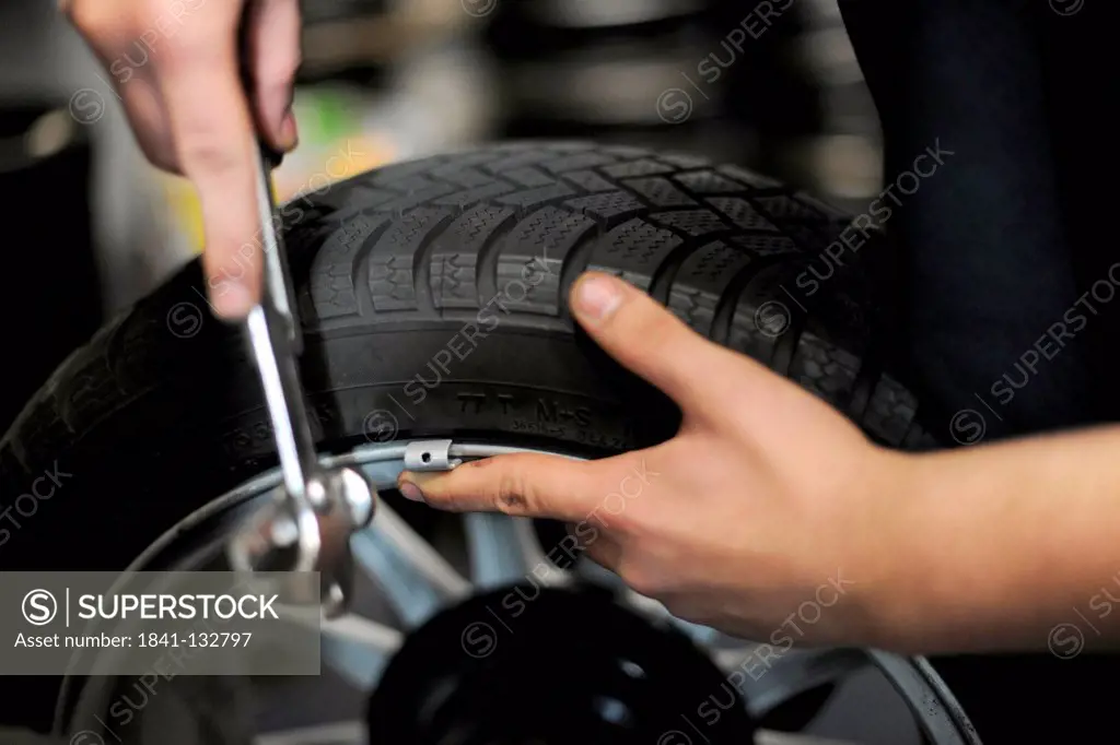 A car mechanic is attaching weights to a tyre in order to balance it.